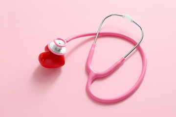 Stethoscope and red heart on color background. Cardiology concept