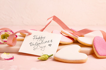 Board with tasty heart-shaped cookies and greeting card on table. Valentines Day celebration