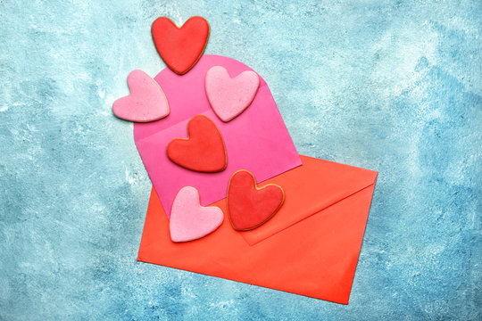 Tasty heart-shaped cookies with envelopes on color background. Valentines Day celebration