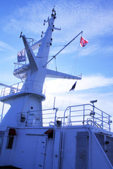 A mast with a flag on the upper deck of a boat, ship, ferry.