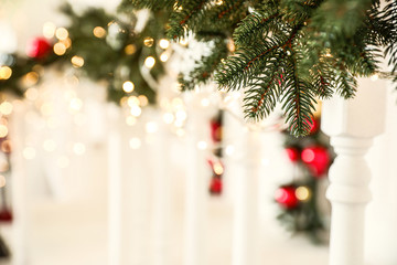 Fir tree branches with glowing garland on railing, closeup