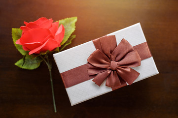 Top view Red rose and white Gift box on wooden table. Valentine's day gift