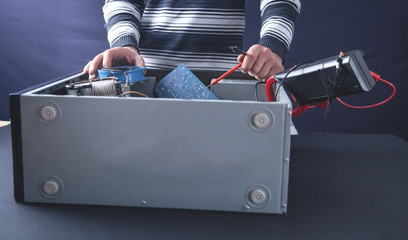 Man checking computer with a multimeter.