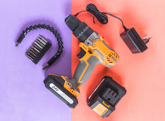 Isolated cordless drill electric power tool set with bits on two tones colorful background.