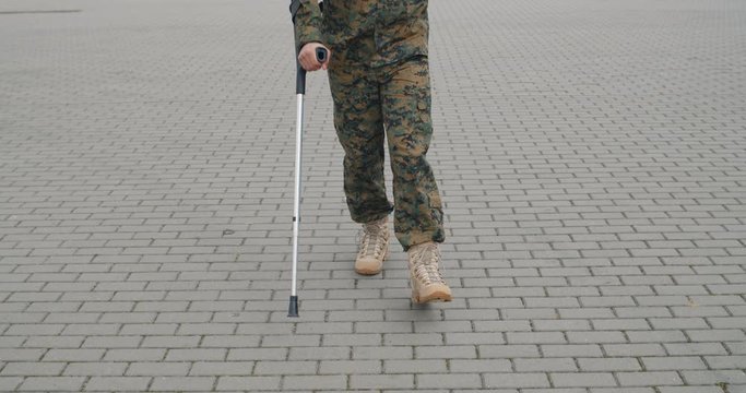 Cropped view of soldier limping and leaning on crutch