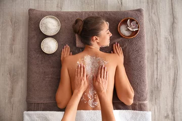 Tuinposter Young woman having body scrubbing procedure with sea salt in spa salon, top view © New Africa