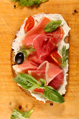 bread slice with cream, prosciutto ham and basil