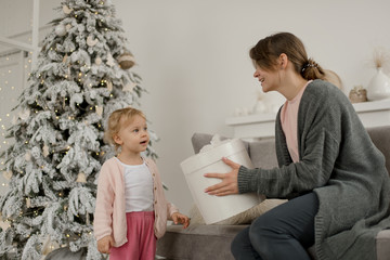 Family Christmas morning in a bright minimalistic living room near the Christmas tree.