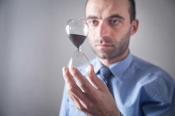 Businessman holding hourglass. Deadline concept
