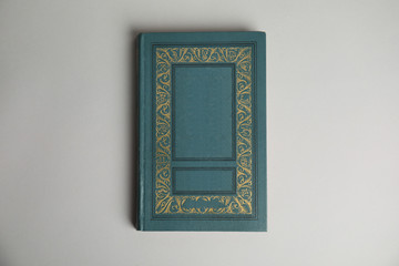Hardcover book on light grey background, top view. Space for design