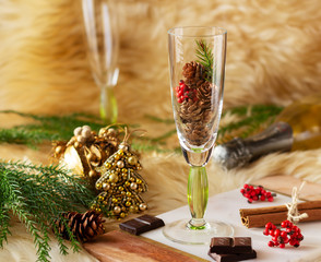 Champagne glass with small cones and Christmas decoration on sheepskin fur. Christmas and New Year composition. Selective focus