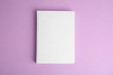 Obraz na płótnie Canvas Book with blank cover on violet background, top view