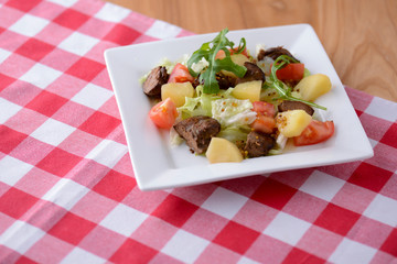 Healthy mix breakfast lunch dinner on a plate, potatoes, grilled meat, tomatoes, salad, sauce in cafe, restaurant.