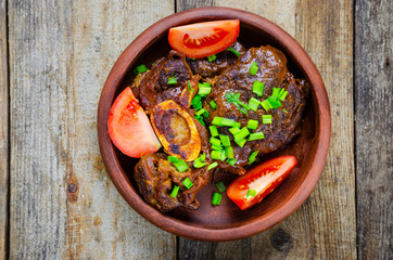 Osso buco steak with tomatoes on a wooden background