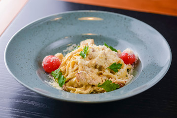 Traditional Italian pasta with cherry tomato, parmezan cheese and parsley served on white plate