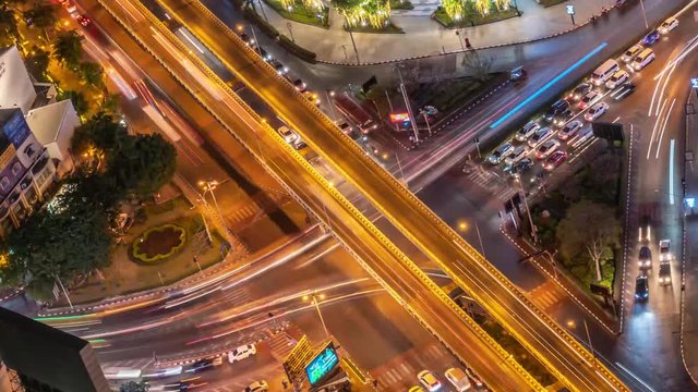 Timelapse of night city traffic on 4-way stop street intersection in bangkok at night, thailand. 4K UHD horizontal aerial view.