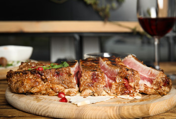 Delicious grilled ribs served on wooden table indoors, closeup