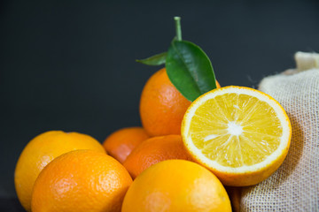 fresh pulpy oranges with a jute package on black background