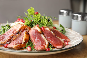 Delicious salad with roasted duck breast served on wooden table, closeup