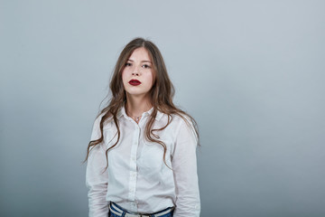 Disappointed young brunette woman over isolated gray background wearing casual white shirt,...