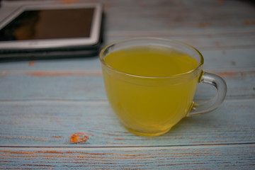 Workspace with tea on vintage wood with digital tablet in the background
