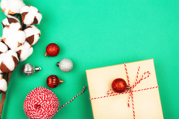 Two Christmas gifts and a cotton branch on green background.