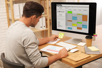 Obraz na płótnie Canvas Handsome man using calendar app on computer in office