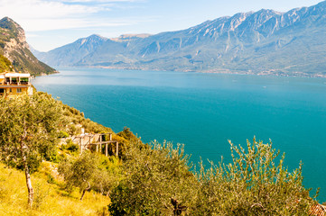 Scenic view from the edge of western coast of Garda lake on beautiful northern Italian nature surrounding this amazing lake. Rocky dolomite mountains landscape around fresh water lake. Lombardy