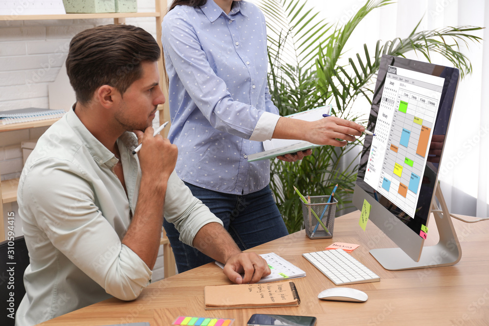 Wall mural colleagues working with calendar app on computer in office