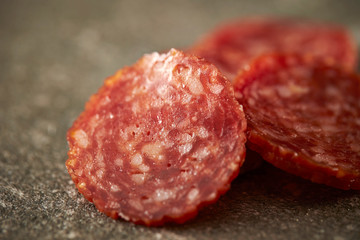 Thin sliced salami sausage on stone background 
