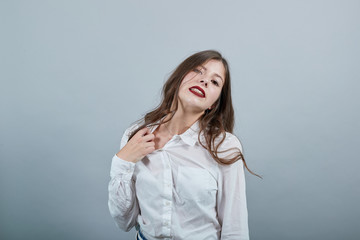 Obraz premium Caucasian young brunette woman over isolated gray background wearing casual white shirt, pulls back his shirt, looking serious. People lifestyle concepte.