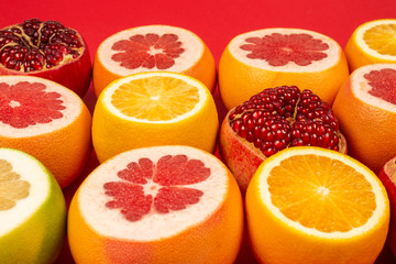 Grapefruit, orange, pomegranate, citrus sweetie on red background.