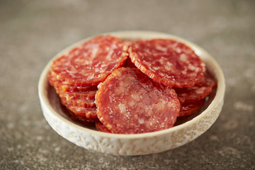 Thin sliced salami sausage on stone background 