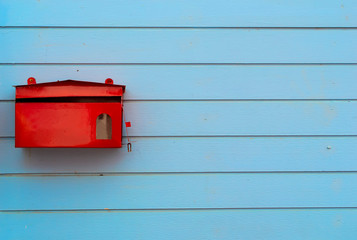 red mailbox on blue plank wood wall