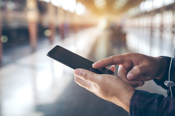 Close-up male hands using smartphone on city searching or social networks concept, hipster man typing an sms message to his friends