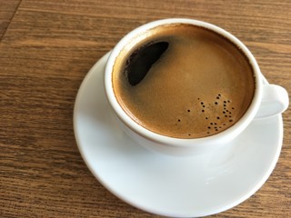 cup of coffee with beans on wooden table