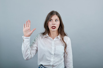 Disappointed attractive brunette woman over isolated gray background wearing casual white shirt, showing palm at camera, looking sad. People lifestyle concepte.