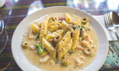 Pasta with white sauce with seafood, on a white plate with Cutlery
