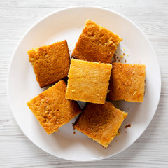 Homemade Cornbread Ready to Eat on a white plate over white wooden background, top view. Flat lay, overhead, from above.