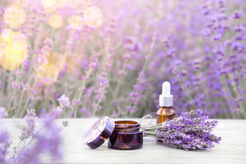 Essential lavender oil in the bottle with dropper on the gray wooden desk. Horizontal close-up. Skin care cream.