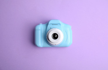 Light blue toy camera on violet background, top view. Future photographer