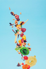 Dried and candied fruits and nuts flying on blue background. Stock photo of healty and nutrient food.