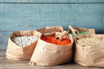 Different grains and cereals in paper bags on wooden table