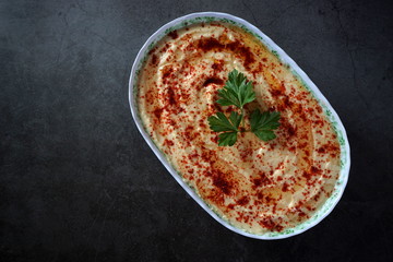 Hummus in a plate on a dark background