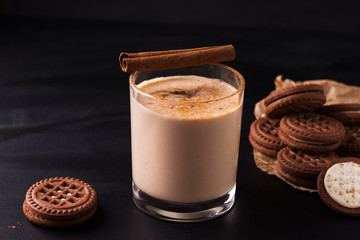 Lassi indian chocolate drink next to cookies on black background