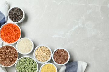 Flat lay composition with different types of legumes and cereals on grey marble table, space for text. Organic grains