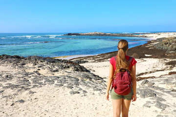 Female hiker backpacker enjoying view of amazing wild beach in Fuerteventura, Canary Islands