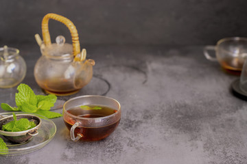 Cup of hot mint tea  and fresh mint leaves on concrete background. Relax beverage concept
