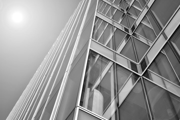 Sun rays light effects on urban buildings in sunset. Modern office building detail, glass surface with sunlight. Business background. Black and white.