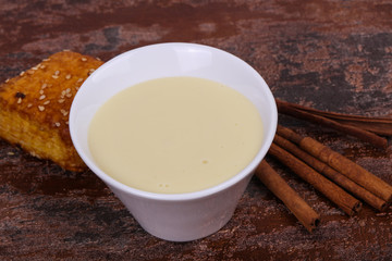 Condenced milk in the bowl with sinnamon and pastry